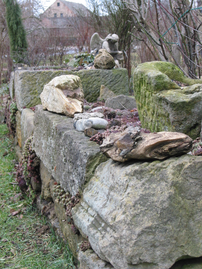 Aus alten Sandsteinen, die aus dem Bauschutt der umliegenden Dörfer zusammengetragen worden entstand eine Trockenmauer.